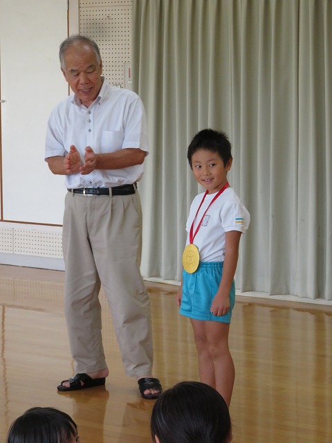 園長先生からメダルをもらう子どもたち　代表して８月生まれのＴくんがめだるをもらいました。